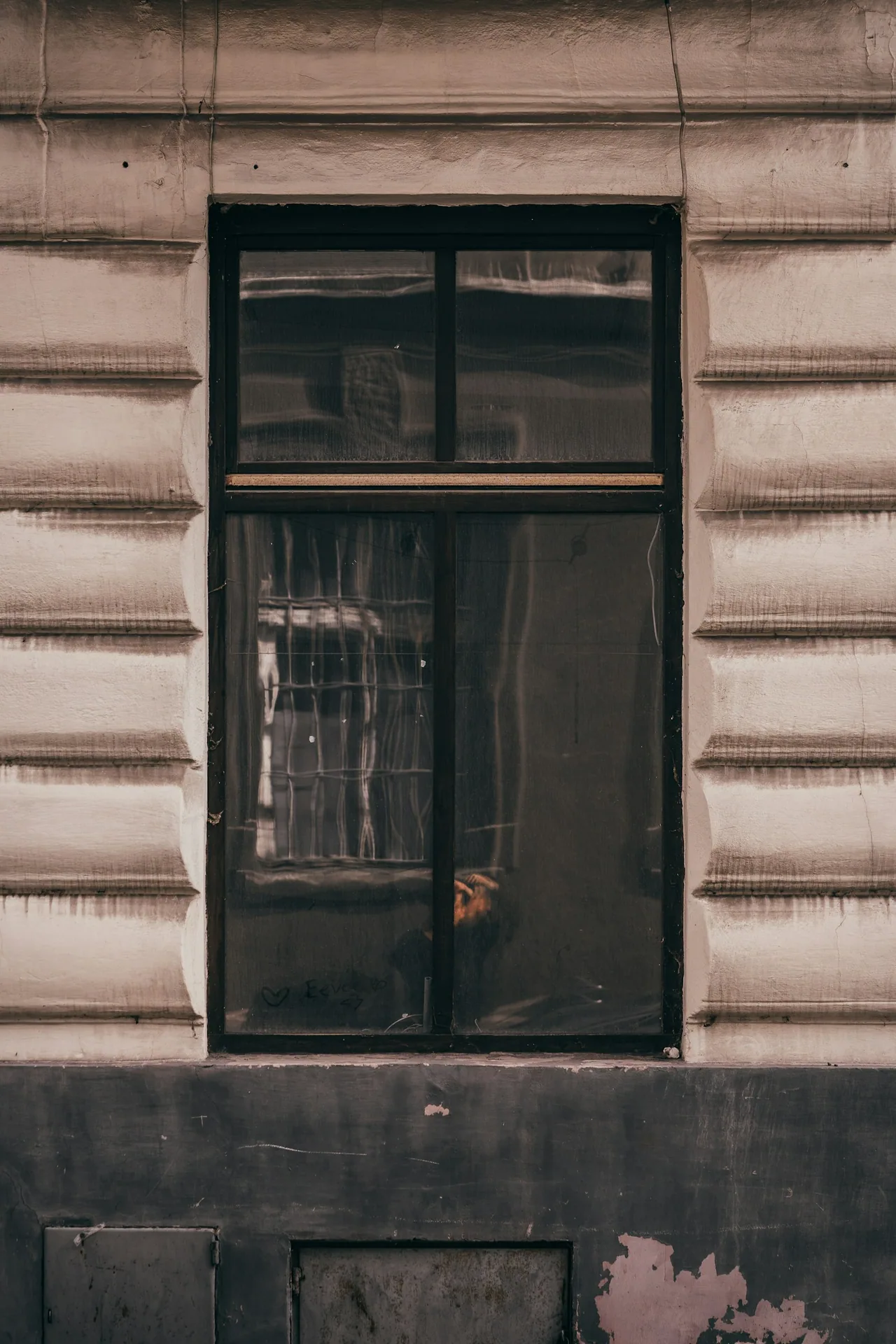 Tall dark window in an aged, textured facade.