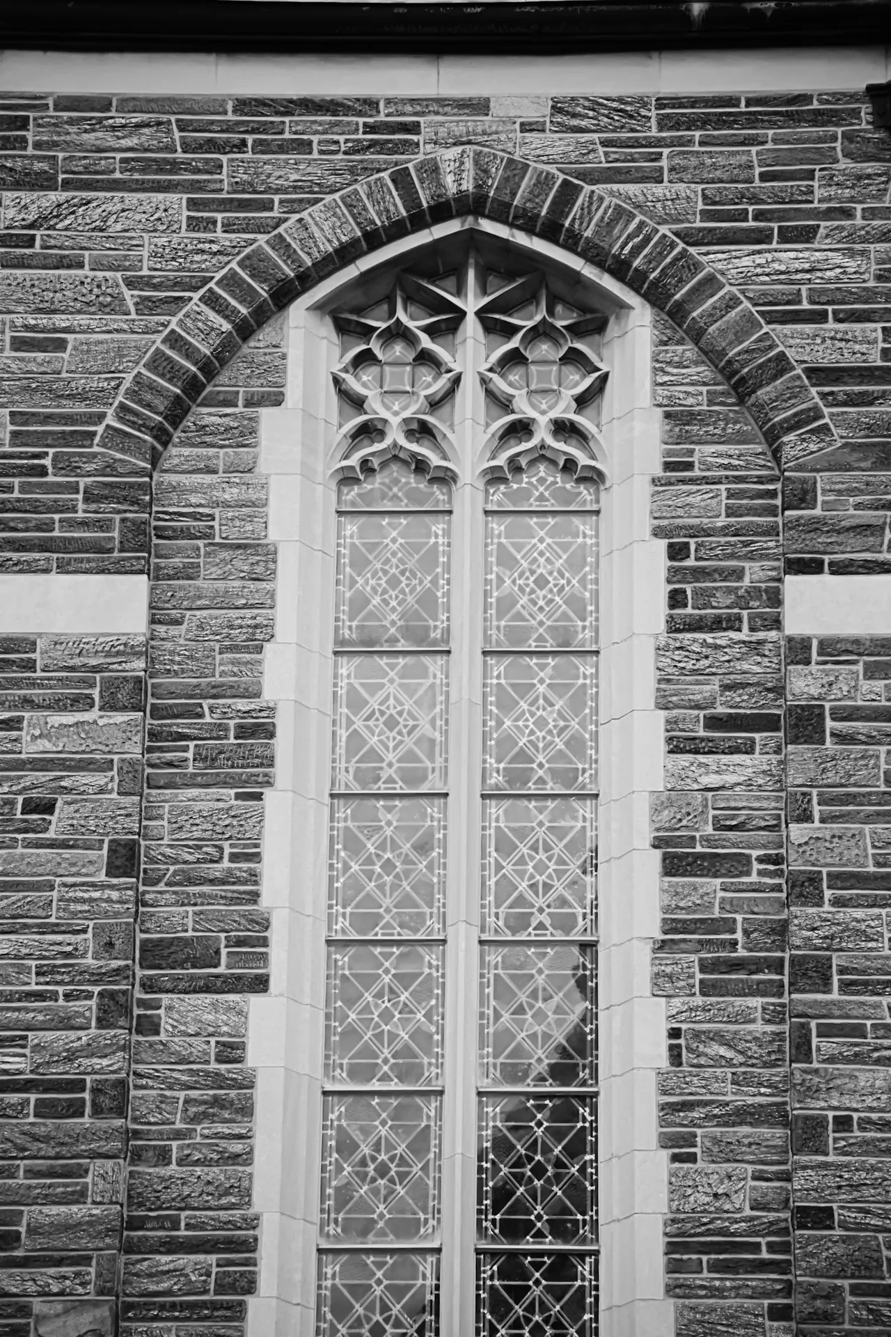 Narrow leaded window framed by layered brickwork.